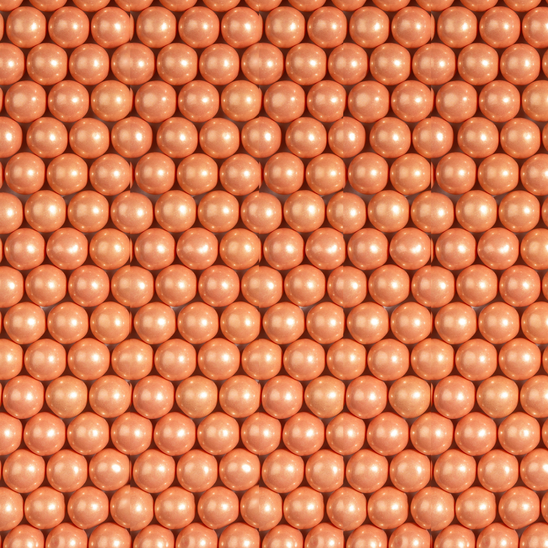 Close-up of shimmer rose gold gumballs arranged in a grid pattern